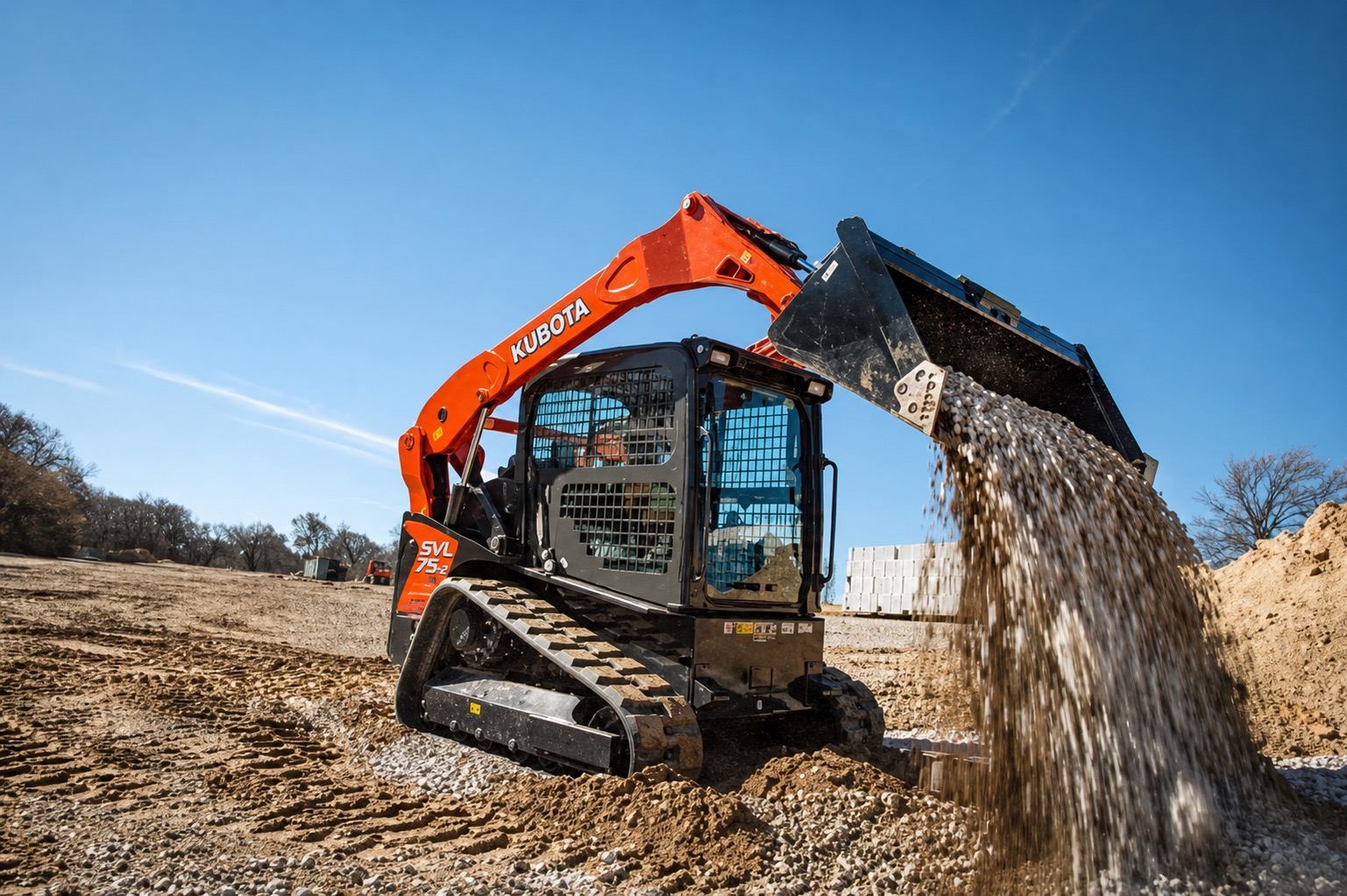 Kubota SVL75-2 dumping gravel on a job site
